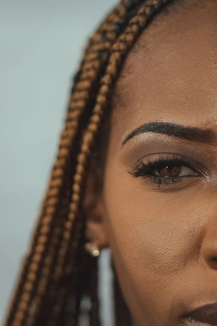 Lash extensions on a Black woman with braids, close-up of lash line