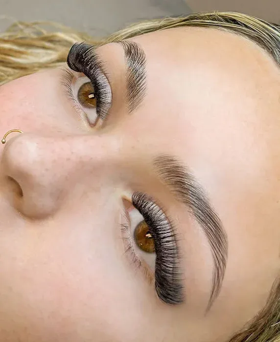 Full volume lash extensions on brown eyes with brushed-up brows